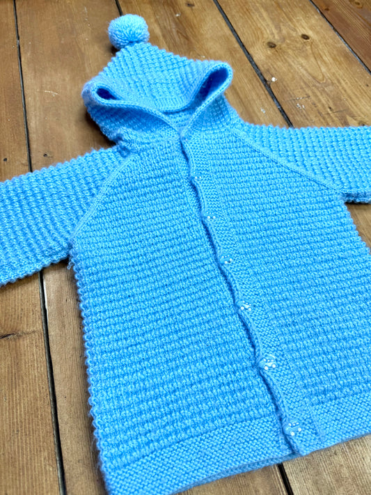 Blue knitted baby cardigan with pom pom hood
