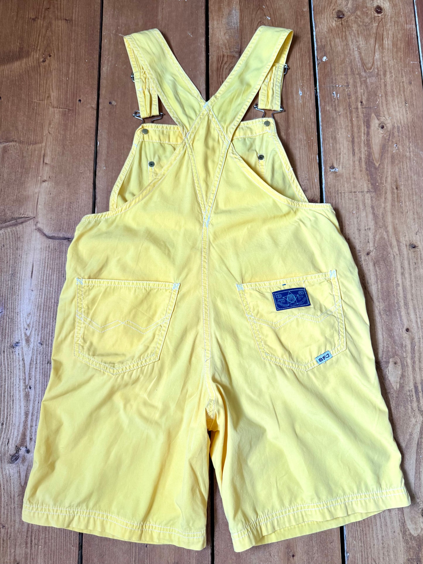 Authentic 90s United Colors of Benetton yellow cotton dungaree shorts, with adjustable straps. Lightweight vintage summer dungarees for kids age 10 years. Handpicked for Bee Tiny.