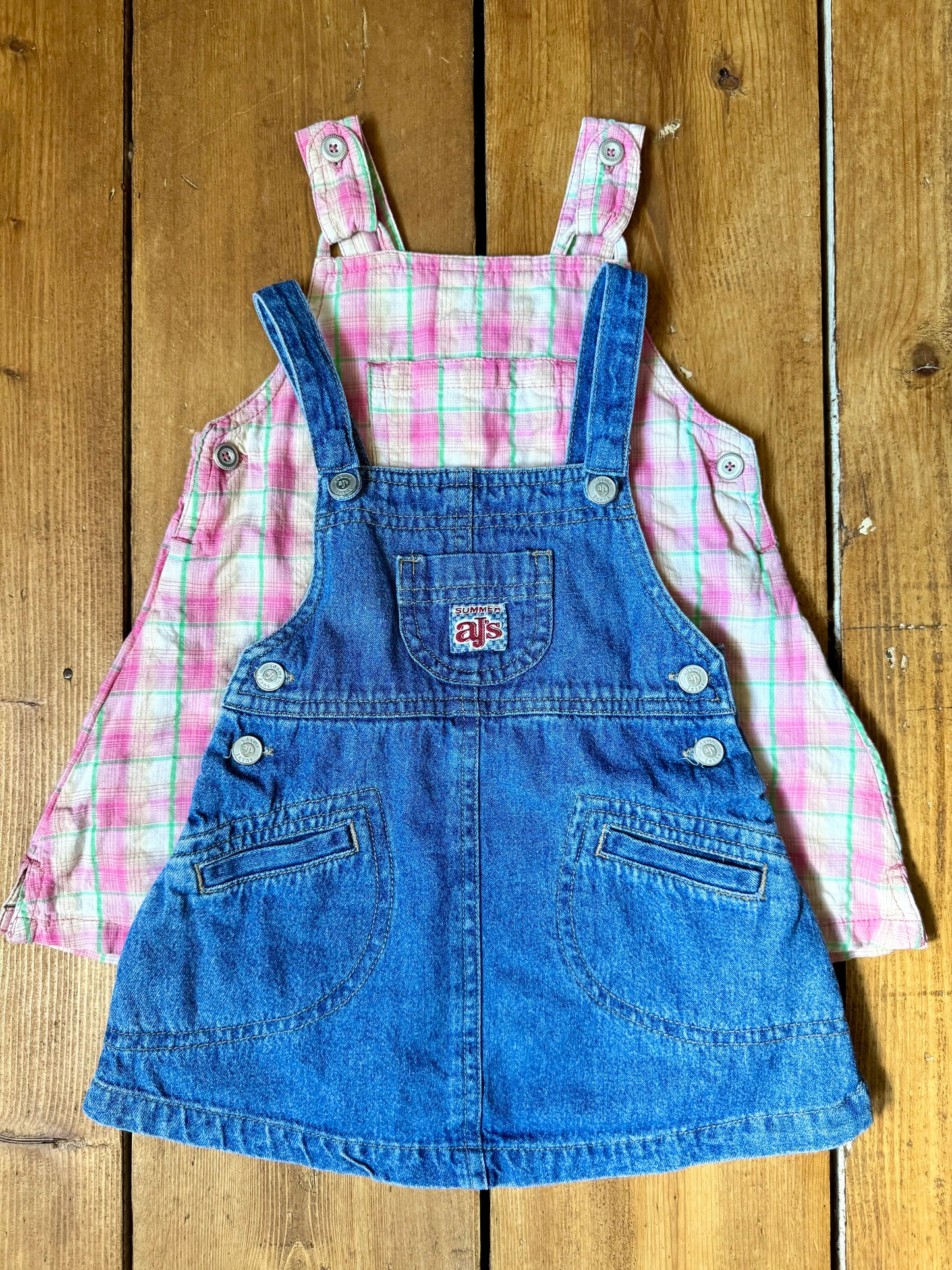Vintage baby dress bundle featuring an Adams denim pinafore and pink gingham summer dress. Two timeless outfits for babies aged 6–9 months. Handpicked for Bee Tiny kids vintage.
