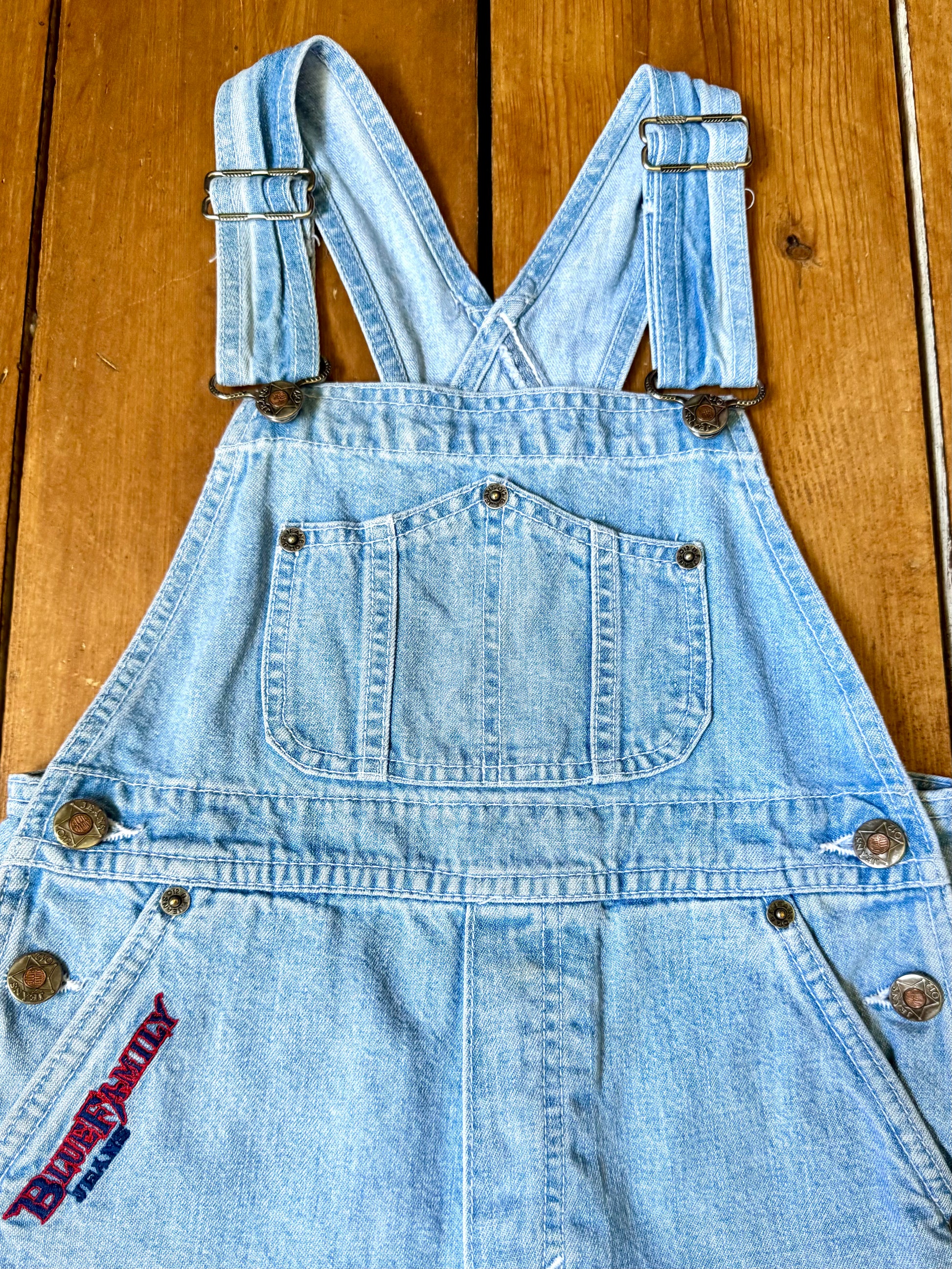 Authentic 90s Blue Family denim short dungarees with adjustable straps, embroidered branding and classic light wash denim. Perfect vintage summer style. Handpicked for Bee Tiny kids vintage. Vintage 90s shortalls.