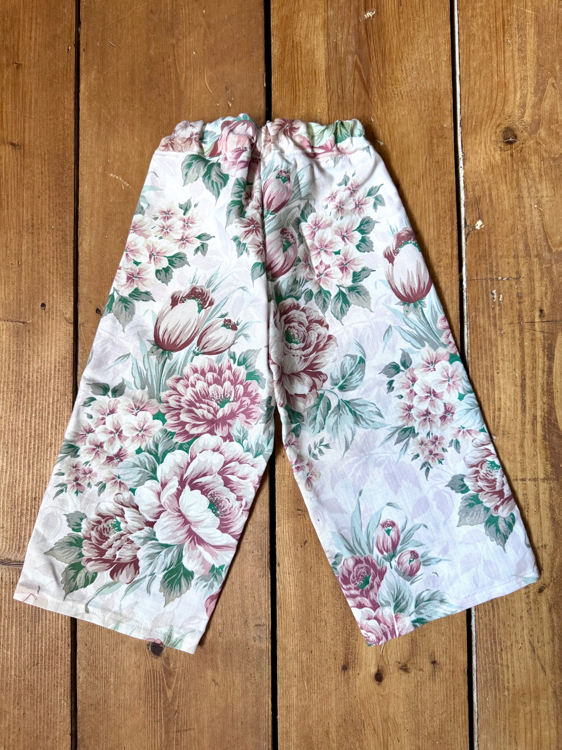 Handmade vintage floral children's set featuring wide-leg trousers and a matching pixie bonnet. One-of-a-kind, sustainably made from rescued fabric. Handmade for Bee Tiny kids vintage.