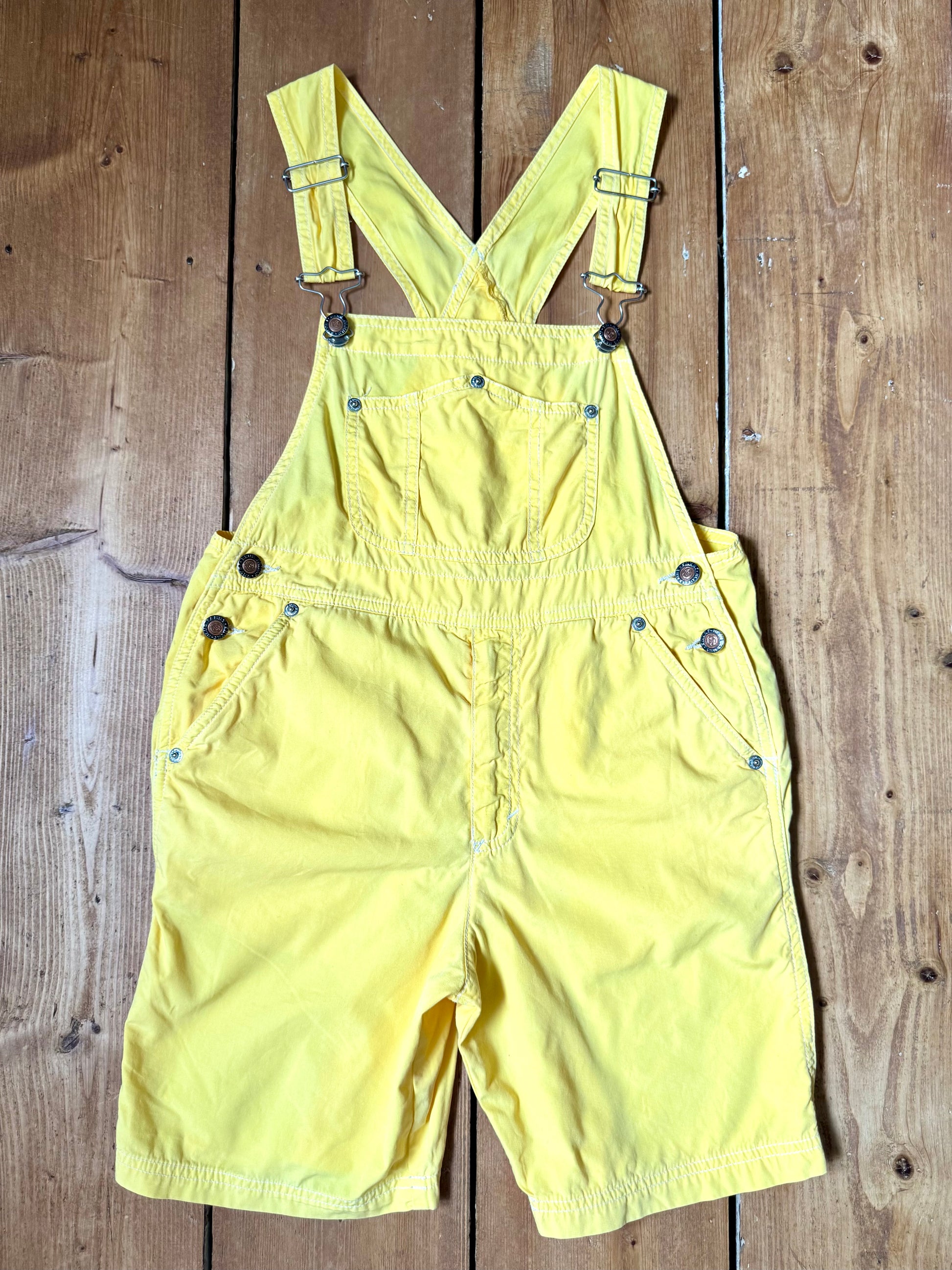 Authentic 90s United Colors of Benetton yellow cotton dungaree shorts, with adjustable straps. Lightweight vintage summer dungarees for kids age 10 years. Handpicked for Bee Tiny.