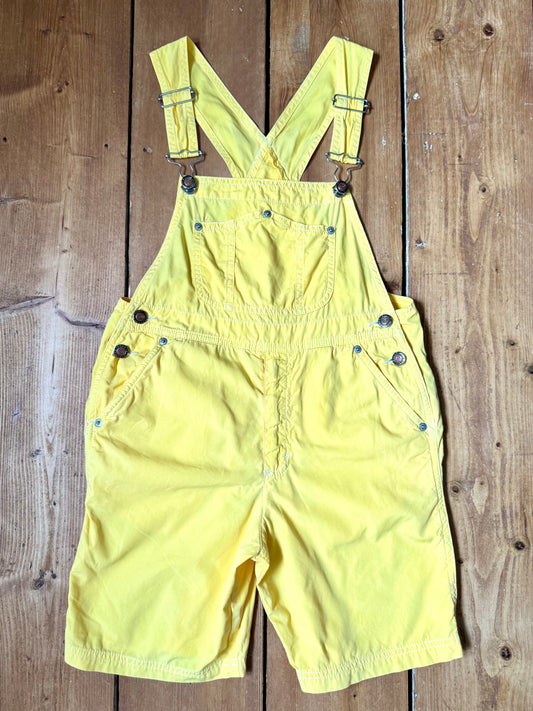 Authentic 90s United Colors of Benetton yellow cotton dungaree shorts, with adjustable straps. Lightweight vintage summer dungarees for kids age 10 years. Handpicked for Bee Tiny.