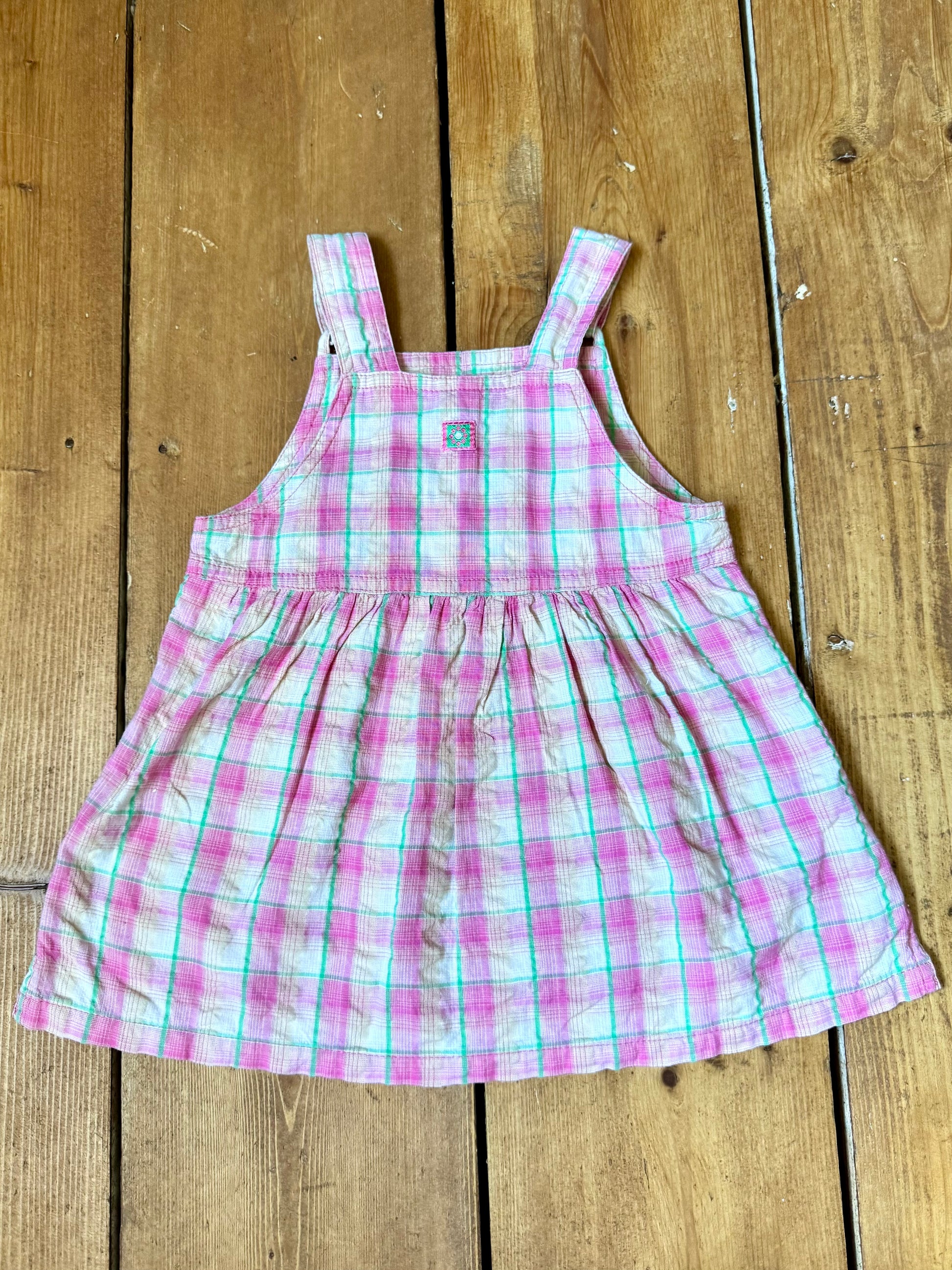 Vintage baby dress bundle featuring an Adams denim pinafore and pink gingham summer dress. Two timeless outfits for babies aged 6–9 months. Handpicked for Bee Tiny kids vintage.