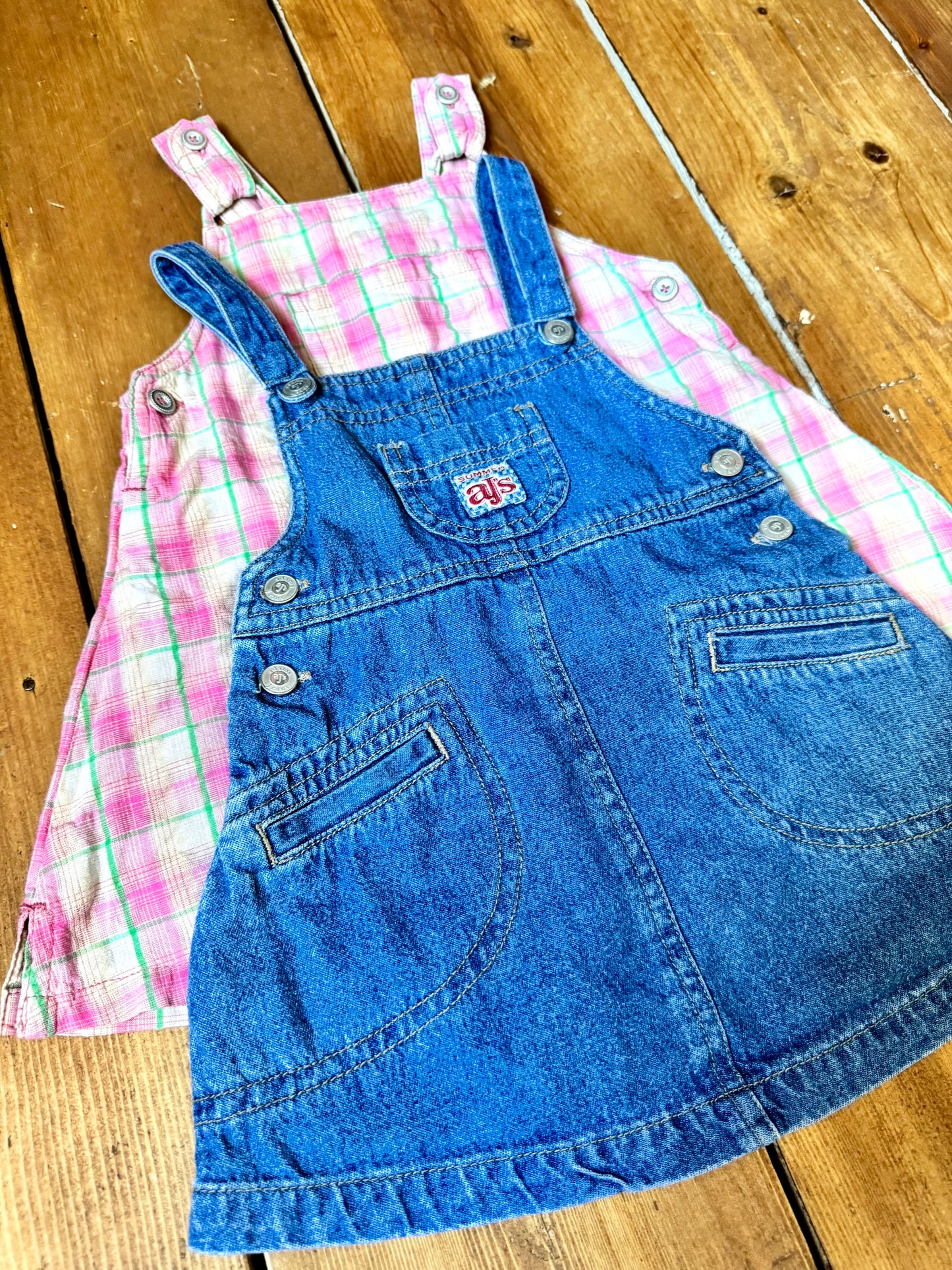 Vintage baby dress bundle featuring an Adams denim pinafore and pink gingham summer dress. Two timeless outfits for babies aged 6–9 months. Handpicked for Bee Tiny kids vintage.