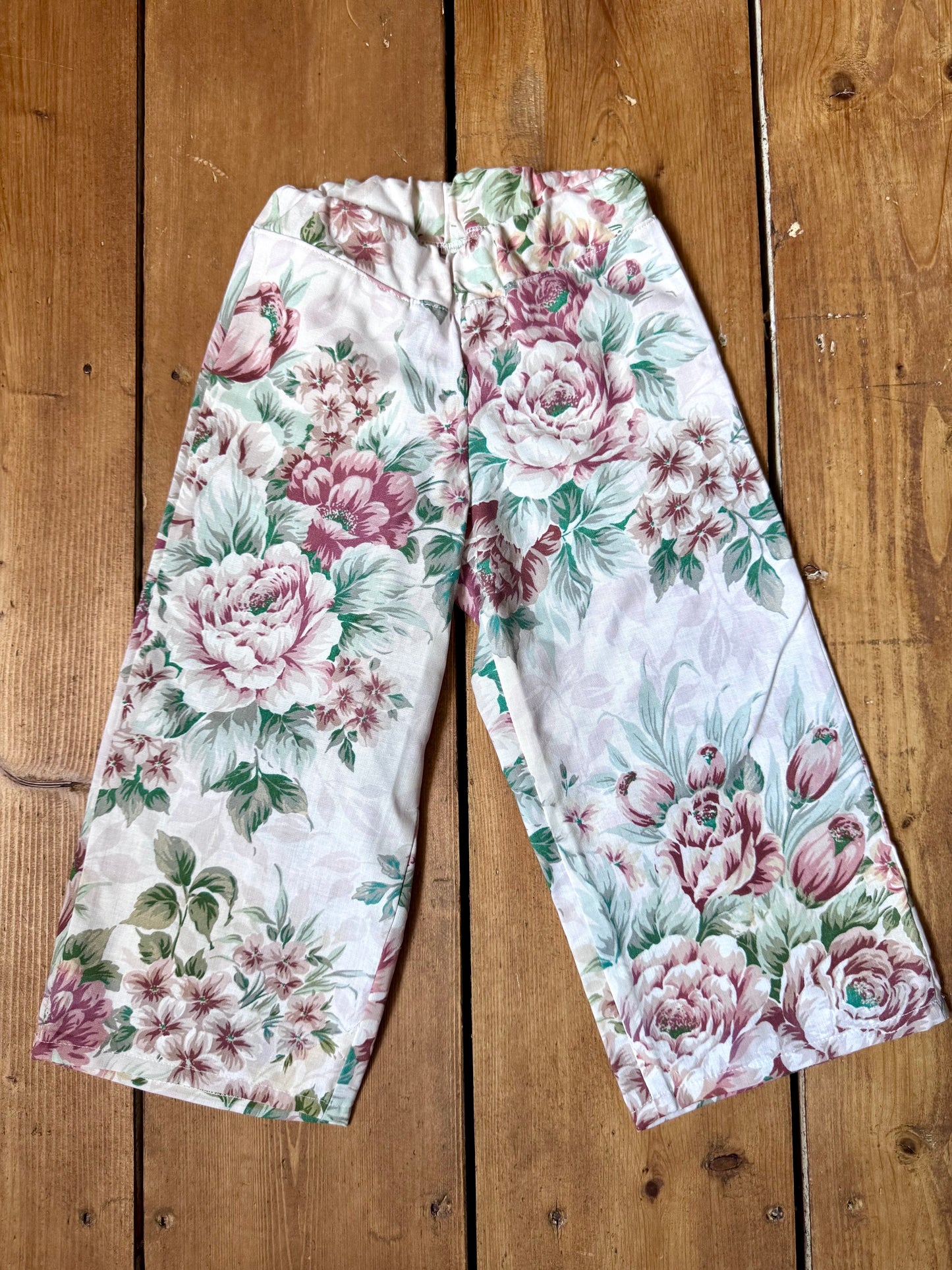 Handmade vintage floral children's set featuring wide-leg trousers and a matching pixie bonnet. One-of-a-kind, sustainably made from rescued fabric.