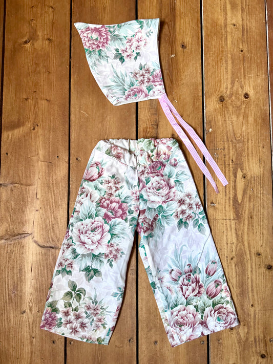 Handmade vintage floral children's set featuring wide-leg trousers and a matching pixie bonnet. One-of-a-kind, sustainably made from rescued fabric.