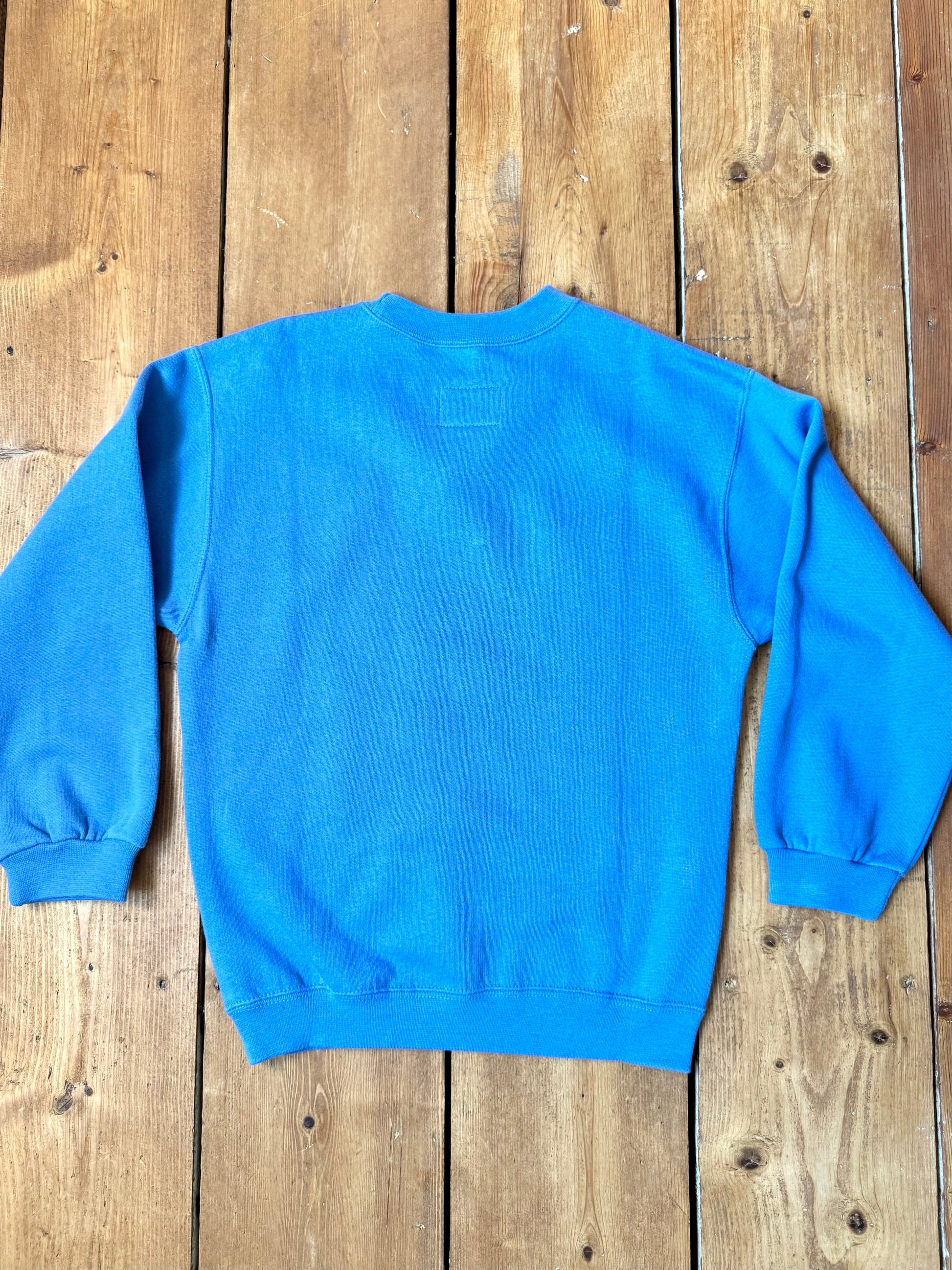Vintage Nike blue sweatshirt with an embroidered Swoosh, soft fleece lining and original swing tag. A timeless unisex kidswear staple, handpicked by Bee Tiny kids vintage.