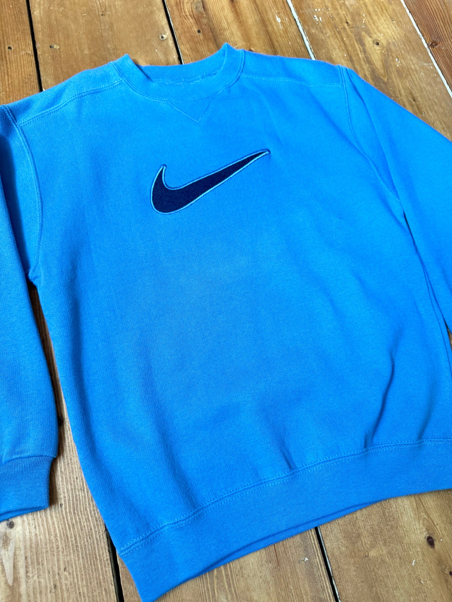 Vintage Nike blue sweatshirt with an embroidered Swoosh, soft fleece lining and original swing tag. A timeless unisex kidswear staple, handpicked by Bee Tiny kids vintage.