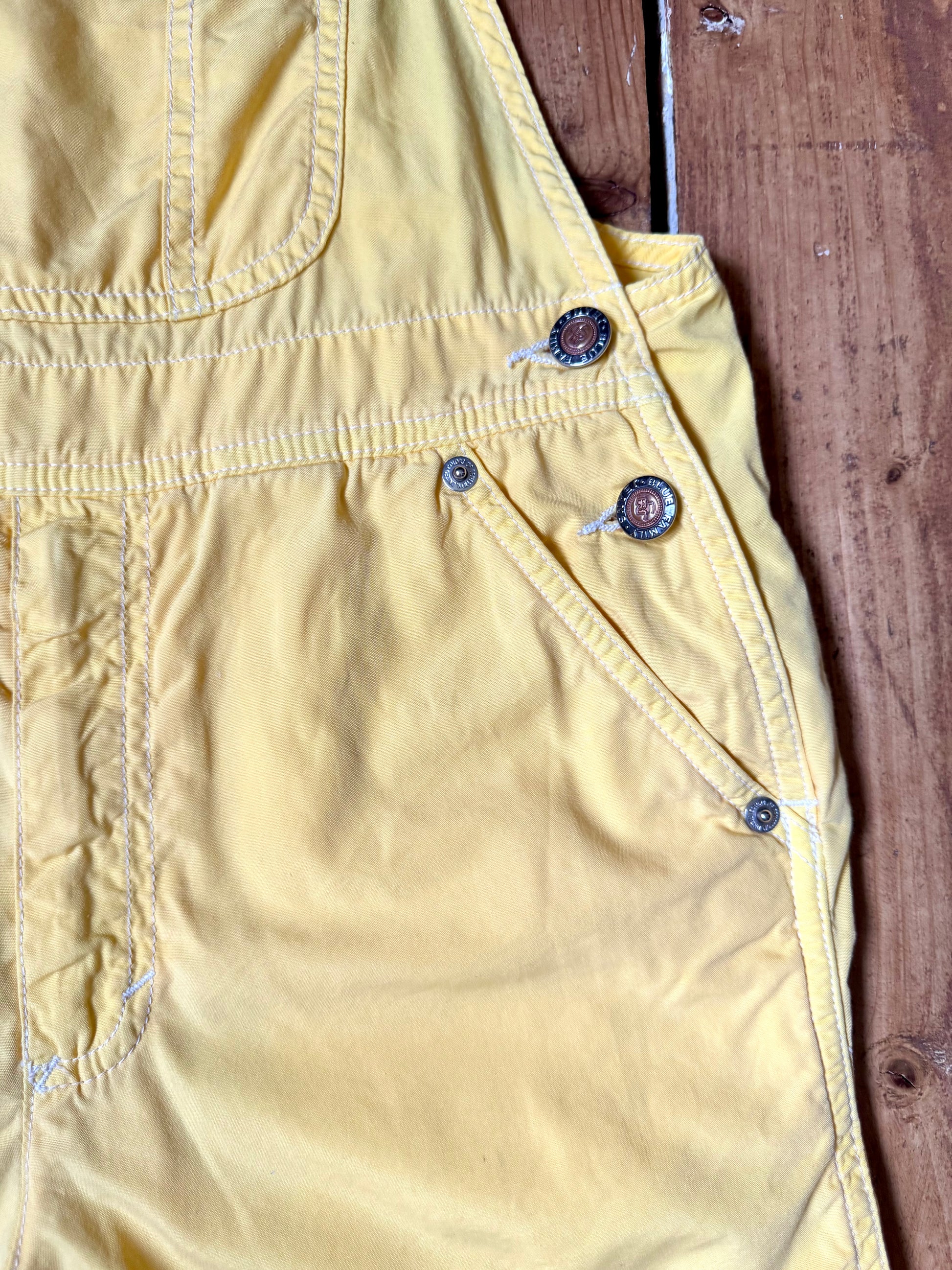 Authentic 90s United Colors of Benetton yellow cotton dungaree shorts, with adjustable straps. Lightweight vintage summer dungarees for kids age 10 years. Handpicked for Bee Tiny.