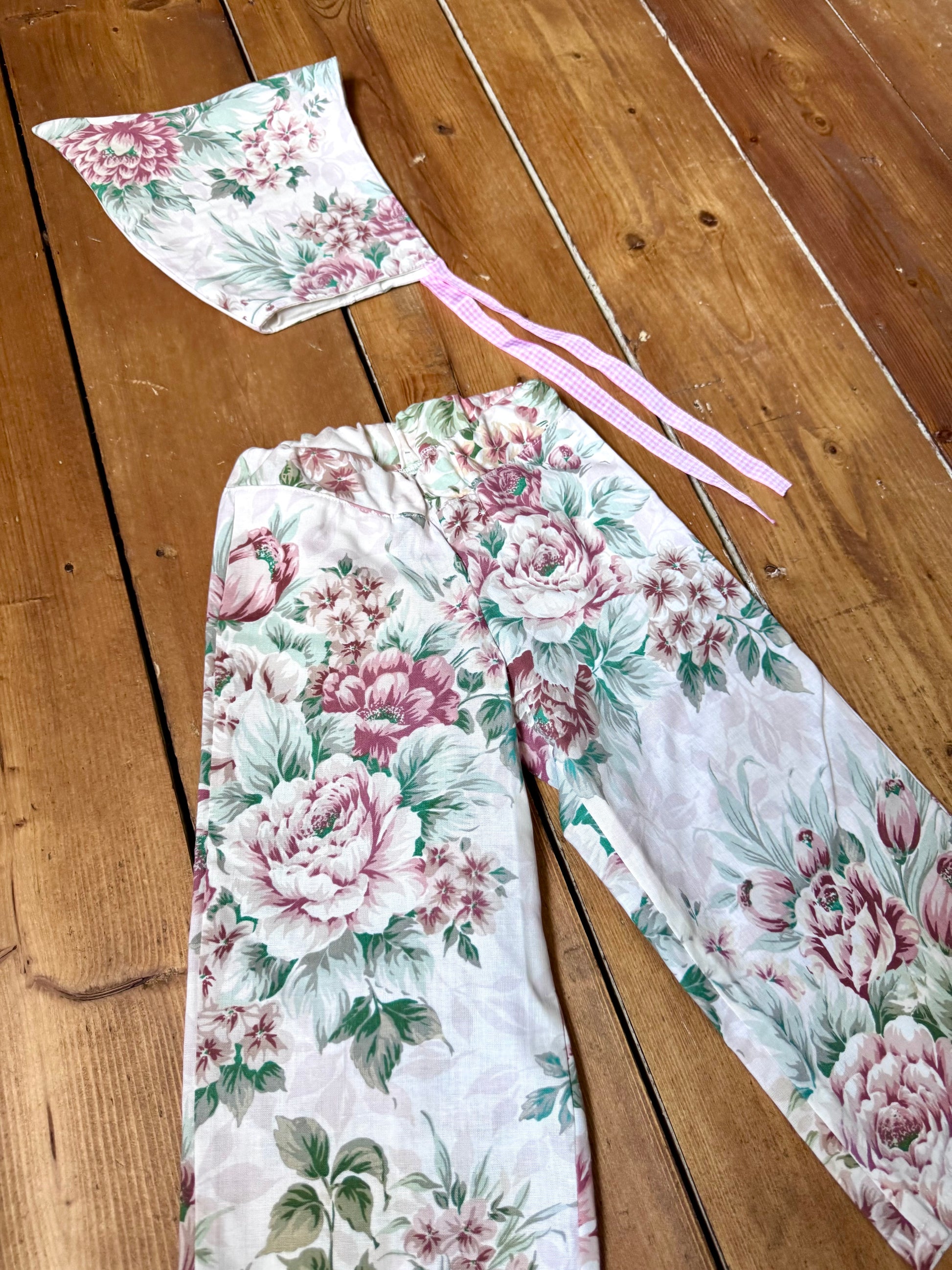 Handmade vintage floral children's set featuring wide-leg trousers and a matching pixie bonnet. One-of-a-kind, sustainably made from rescued fabric.