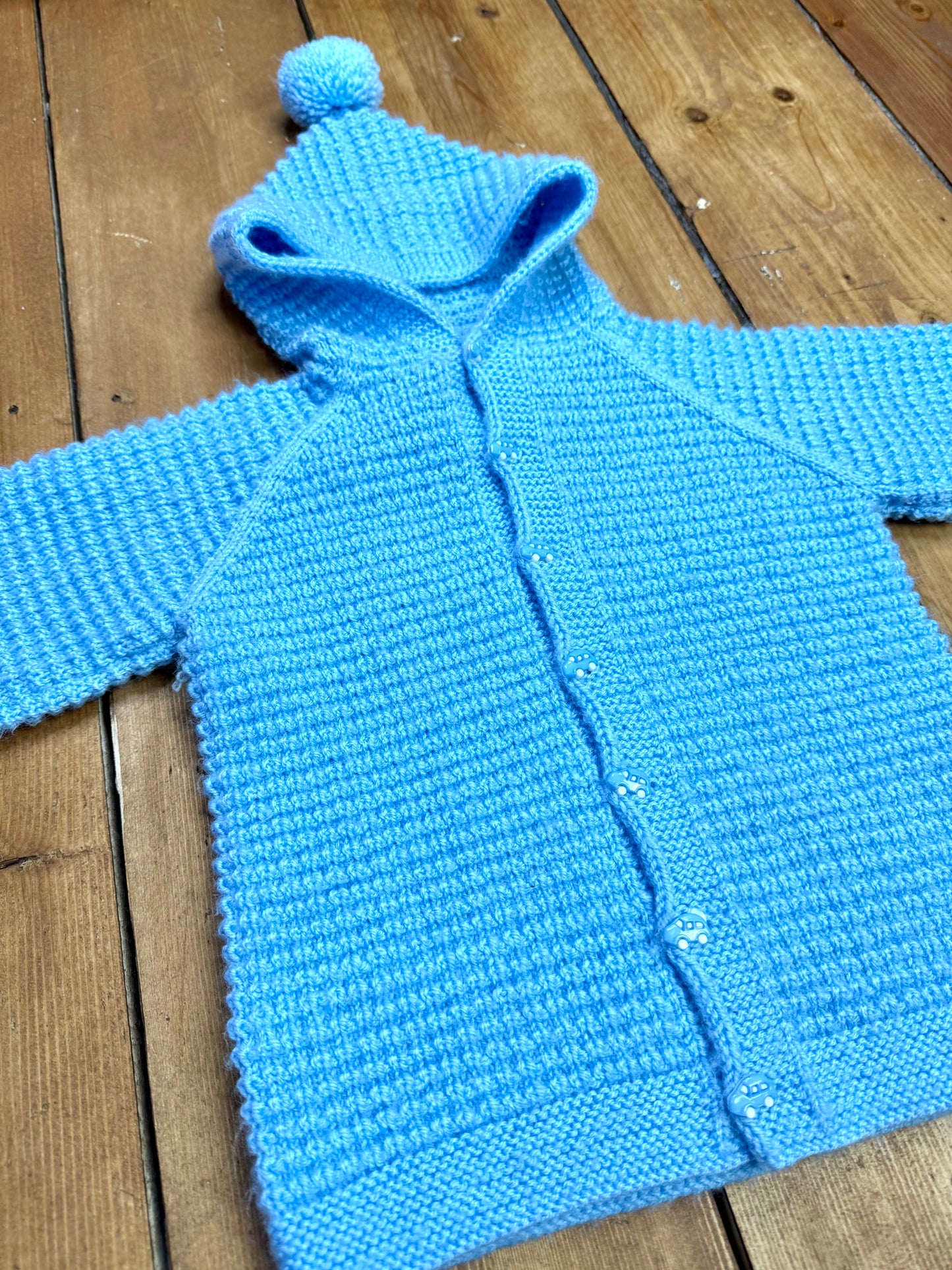 Blue knitted baby cardigan with pom pom hood