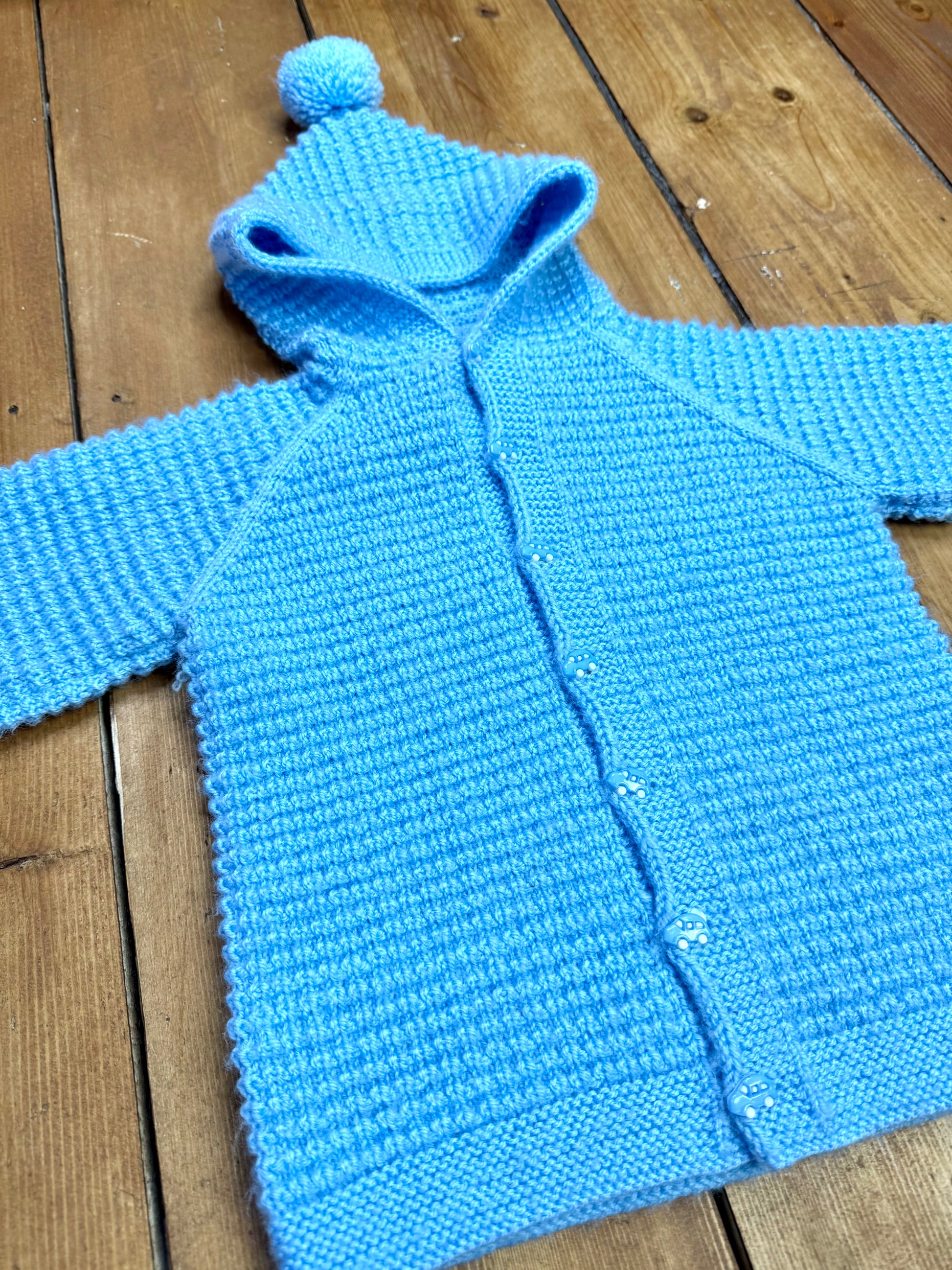 Blue knitted baby cardigan with pom pom hood