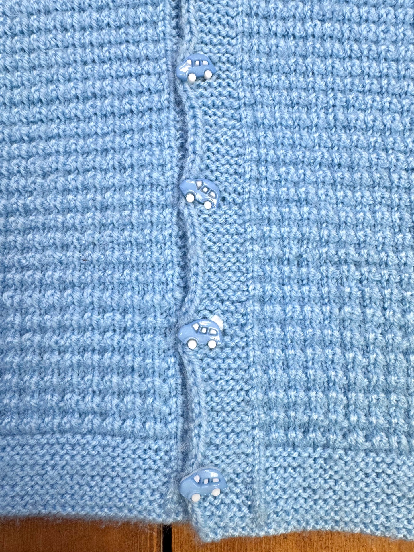 Blue knitted baby cardigan with car buttons