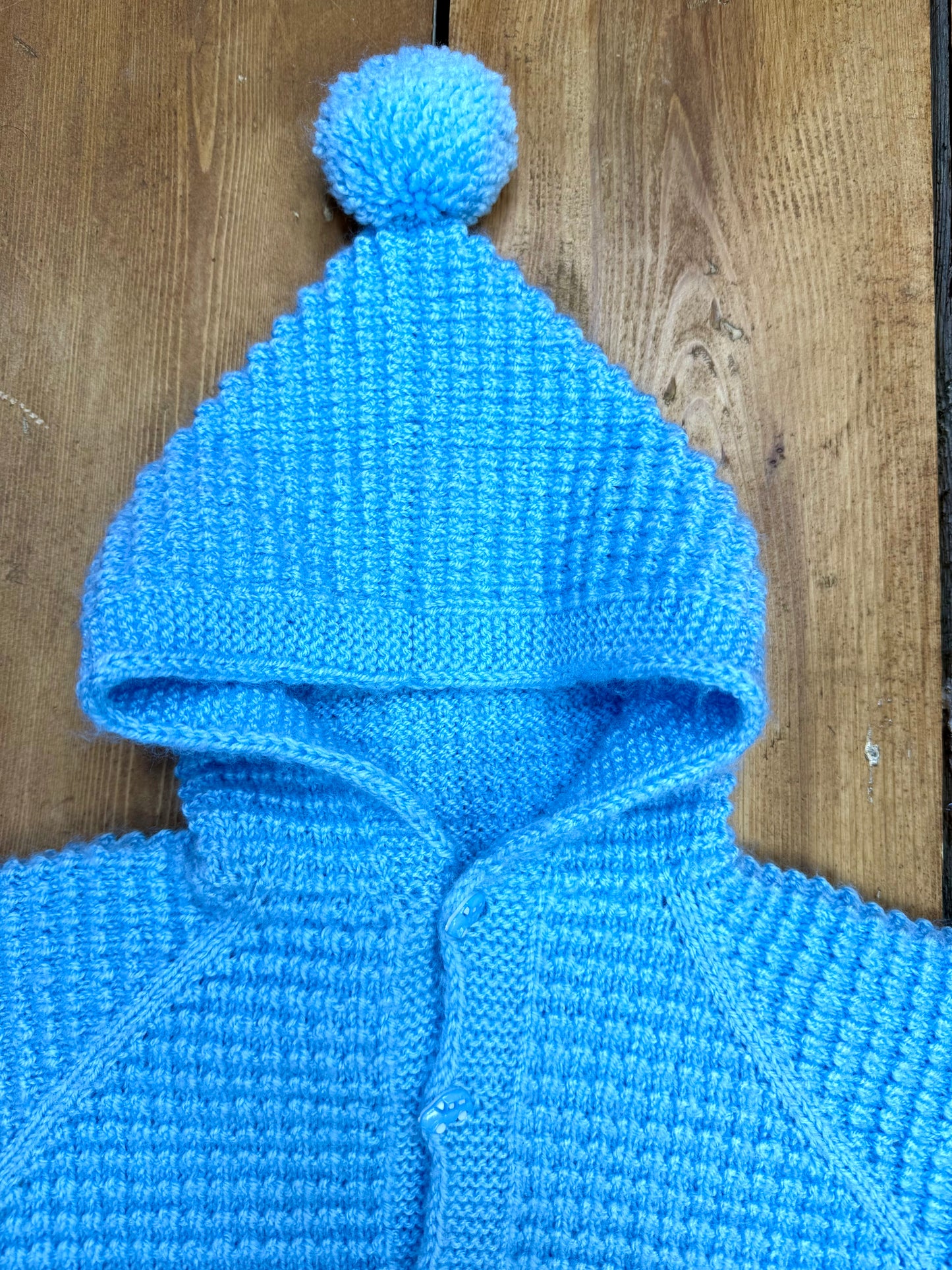 Blue knitted baby cardigan with pom pom hood