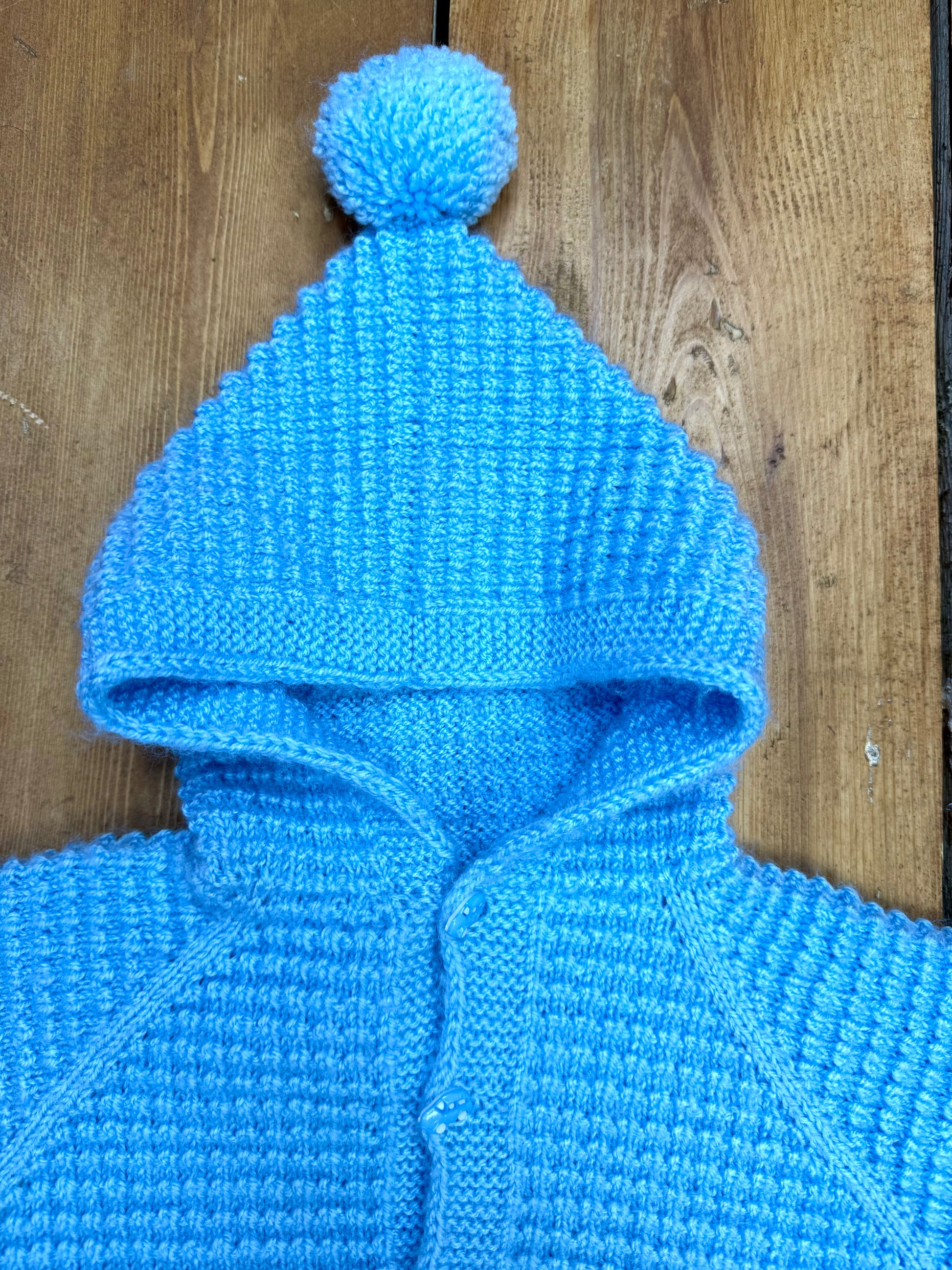 Blue knitted baby cardigan with pom pom hood