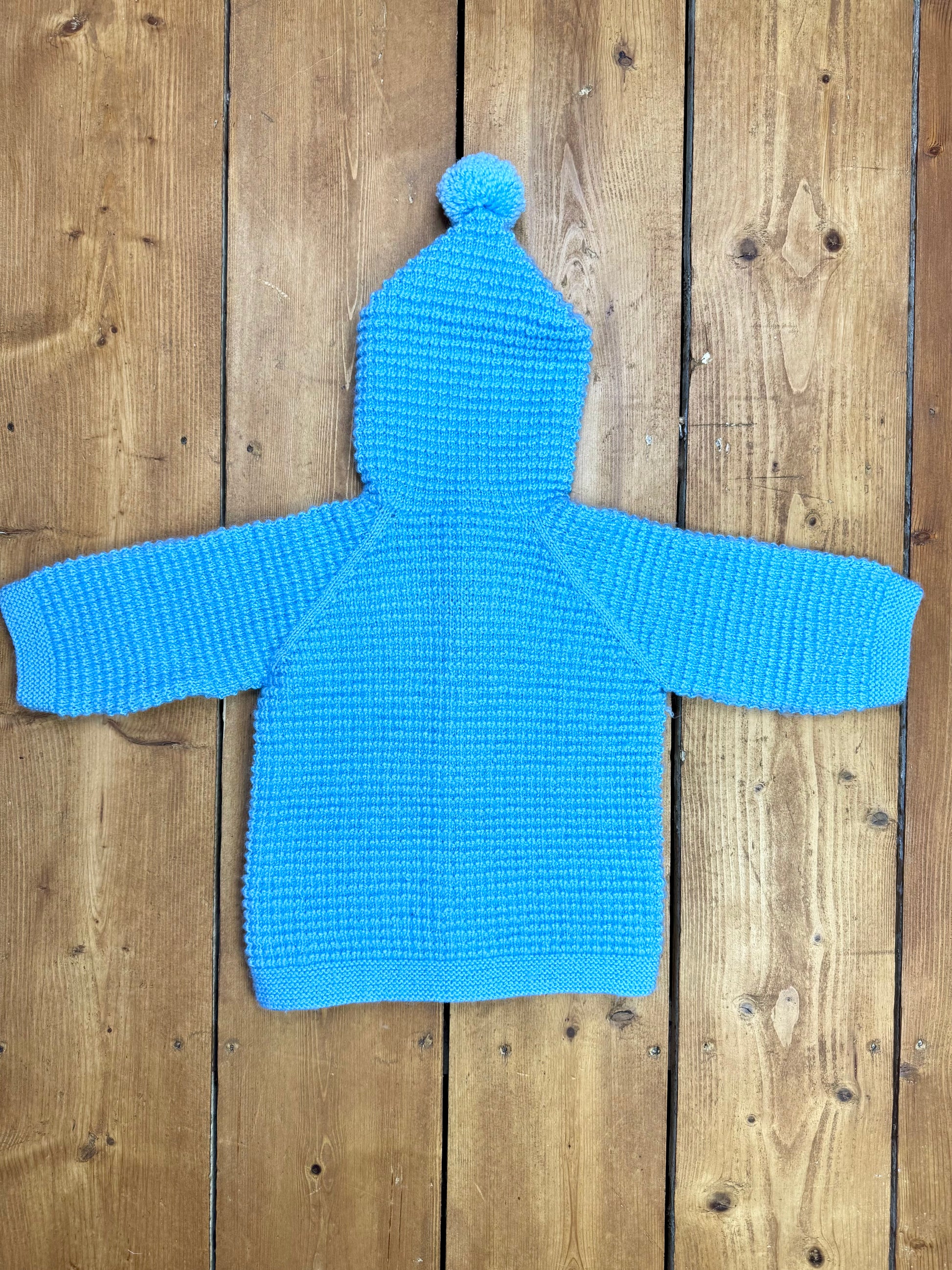 Blue knitted baby cardigan with pom pom hood